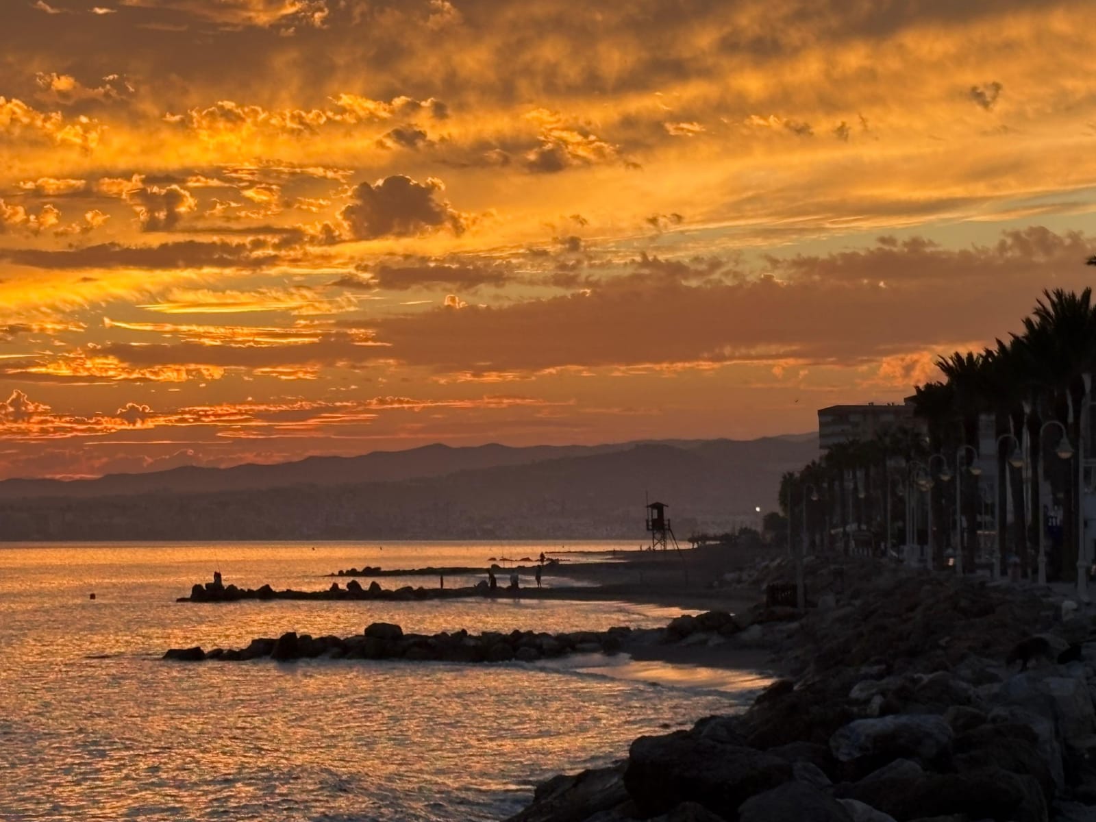 Zachód słońca w Algarrobo na Costa del Sol: falochrony, plaża i promenada z palmami