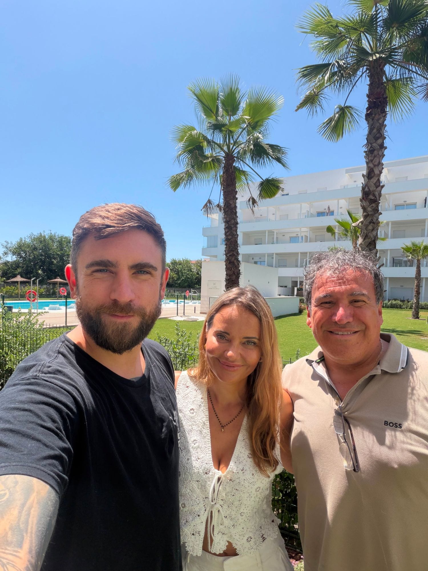 Od lewej: Idzi Kisza, Sylwia Antczak Baranowska i Gilberto Tejada przed apartamentowcem z palmami
